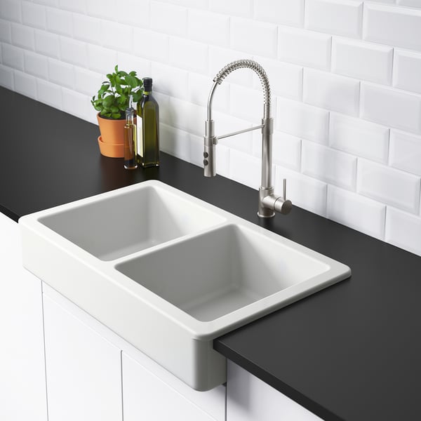 Modern kitchen sink with pull-down tap. The sink has a double basin design. The tap a flexible hose for easy use.