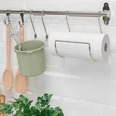 Kitchen rack holding utensils, a green cup, and a paper towel roll.