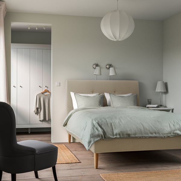 Beige IDANÄS bed, minimalist room, 2 lamps, chair, coat closet, rug, round light.