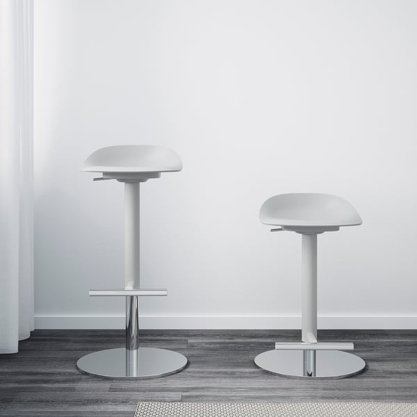 Two modern bar stools with adjustable heights, round metal bases, and white scooped seats against a white wall. Ideal for bars between 90-110 cm.