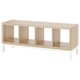 A KALLAX light wood shelving unit with white metal legs. It four open storage sections.