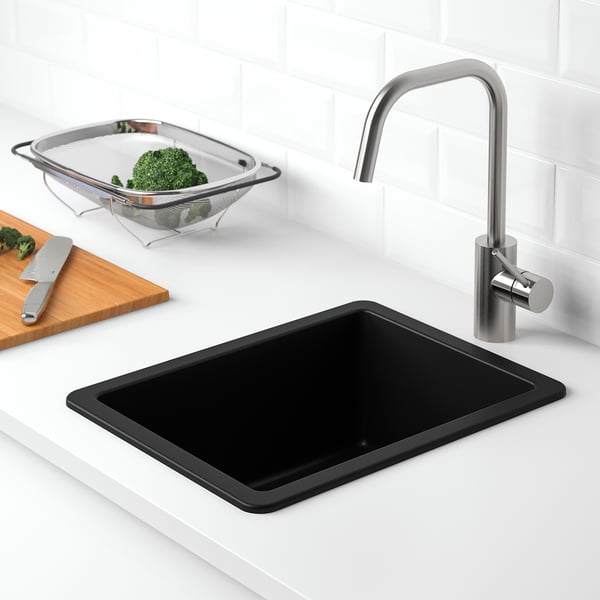 Modern kitchen sink with black granite and chrome tap. Broccoli shows practical use.