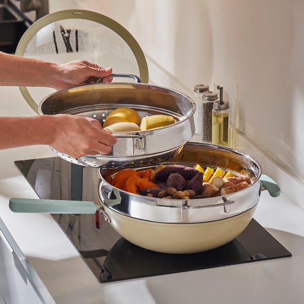 Person uses steamer insert to cook vegetables and eggs in one pot, saving energy and space.