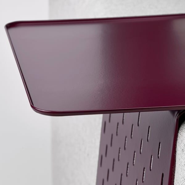 Close-up of maroon metal tray on armrest, smooth surface, perforated edge.