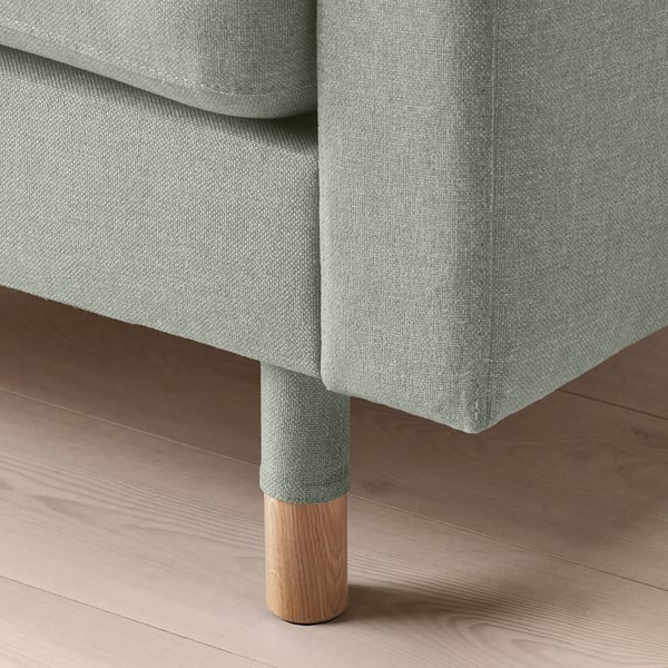 A modern sofa with soft grey fabric, designed for comfort. Showcasing tight seams and supportive cushions, it sits on wooden legs for stability.