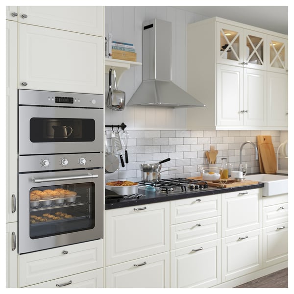Modern kitchen with stainless steel oven and cooktop, white cabinets, and black countertop.