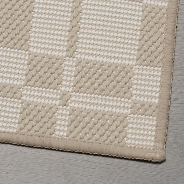 Close-up of a textured rug corner with a diamond pattern.