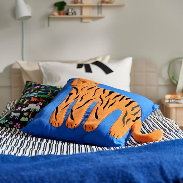 Blue & black bed, orange tiger cushion, cosy pillows.