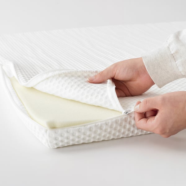 Person zips up white mattresses, showcasing memory foam padding and removable cover for easy cleaning.