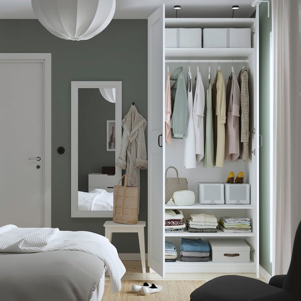 Modern bedroom with white PAX wardrobe, mirror, and pendant light.