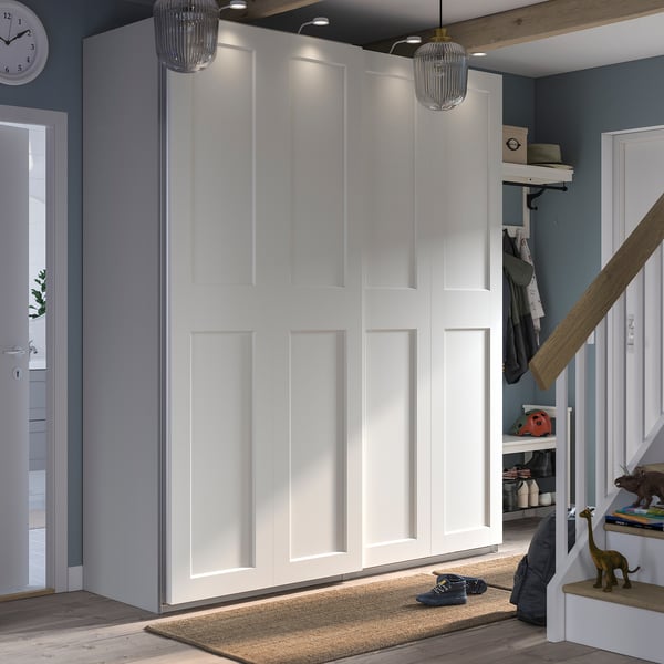 Modern entryway with white PAX wardrobe, two pendant lights, shoe rack, coat hooks, toys, and a clock.