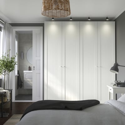 Modern bedroom with white PAX wardrobe, integrated lighting, and minimalist design.