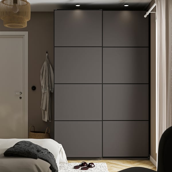 Modern bedroom with black PAX wardrobe, cosy bed, bedside table, pendant lamp, and wicker basket.