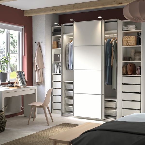 Modern bedroom with a white sliding door wardrobe, desk, chair, and brown accents.