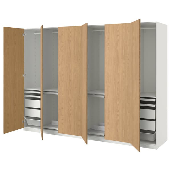 An IKEA PAX wardrobe in white and oak. It has multiple doors, with some open to reveal storage options like shelves and drawers.