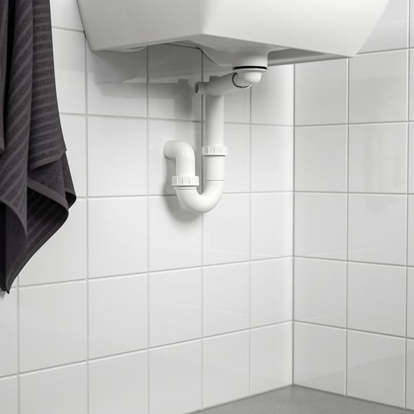 A bathroom drain trap installed under a sink, with a strainer and adjustable length, fitting inside cabinets or connecting to drains or appliances.