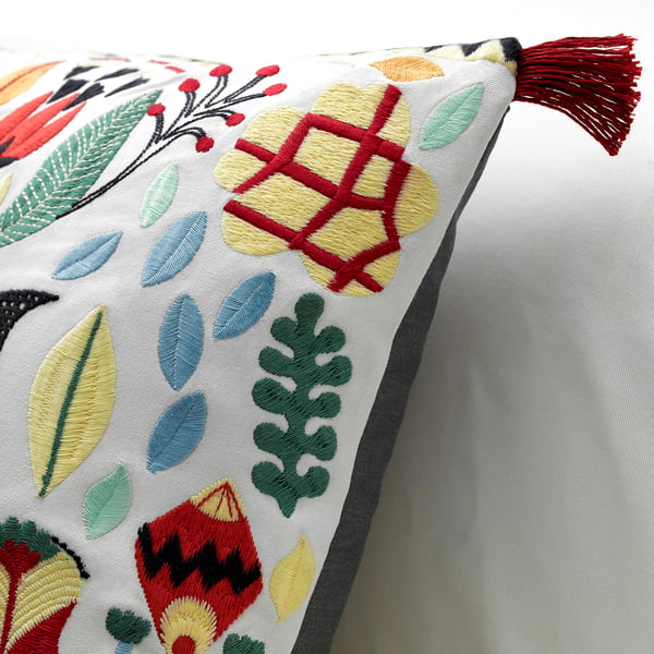 Embroidered cushion with bright leaf patterns, red tassel, and intricate stitching.