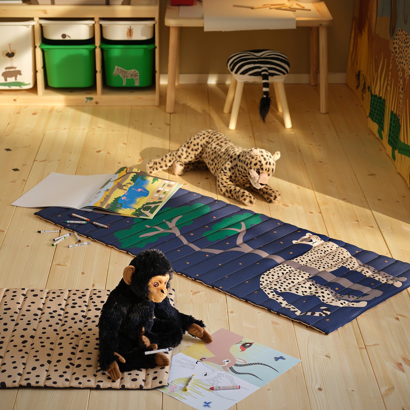Safari-themed play mat with cheetah print, wooden floor, stuffed animals, and kids drawings.