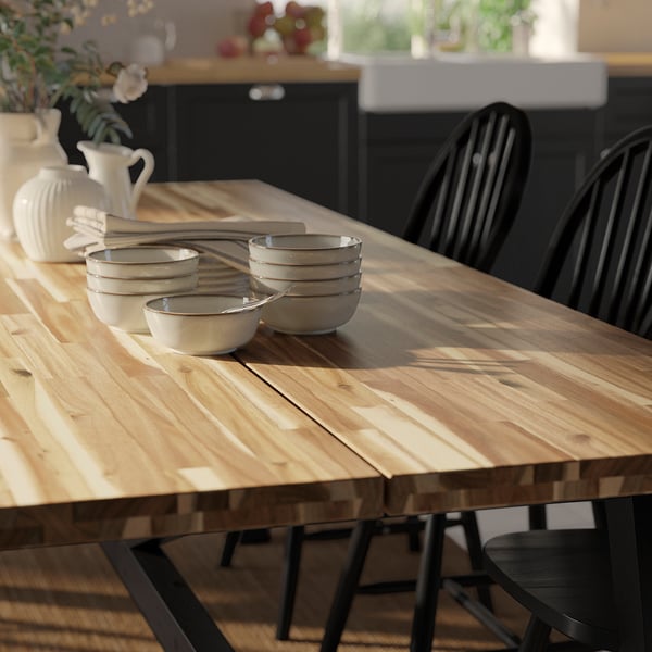 Wooden table with dark metal chairs. Bowls and a jug on table.
