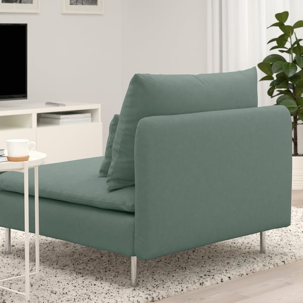 Modern green SÖDERHAMN sofa with deep seats and loose cushions, near a small table with a coffee cup.