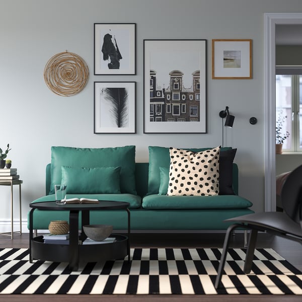 Modern living room with teal SÖDERHAMN sofa, black & white chequered rug, green throw pillow, coffee table, and wall art.