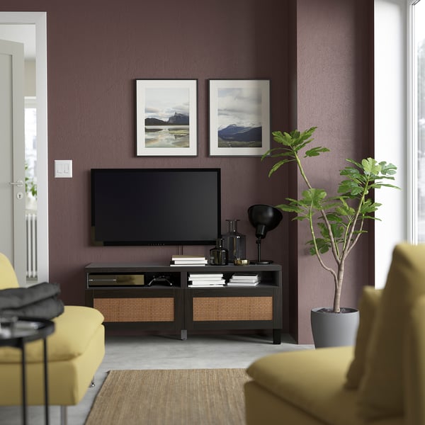 Modern living room with dark purple wall, tv on stand, yellow couch, and large plant.