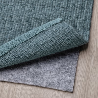 Flatwoven wool rug on wooden floor with anti-slip underlay, demonstrating easy maintenance and ideal use under furniture.