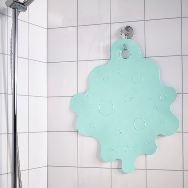 Turquoise bath mat hangs on wall hook, secured by suction cups, designed to prevent slipping.