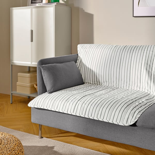 Modern living room with striped pet blanket on grey sofa.
