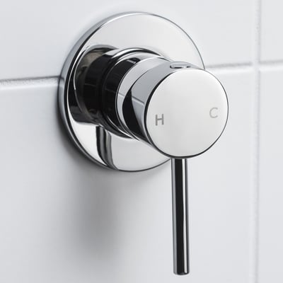 Chrome shower mixer with h/c knobs, close-up on tiled wall, sleek design.