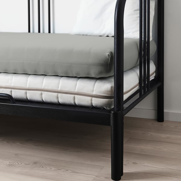 A black metal bed frame with a grey fitted sheet and mattress, showcasing adjustable height up to 16 cm.
