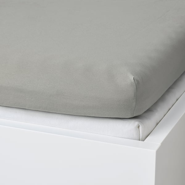 Grey cotton sheet on white bed, stays in place.