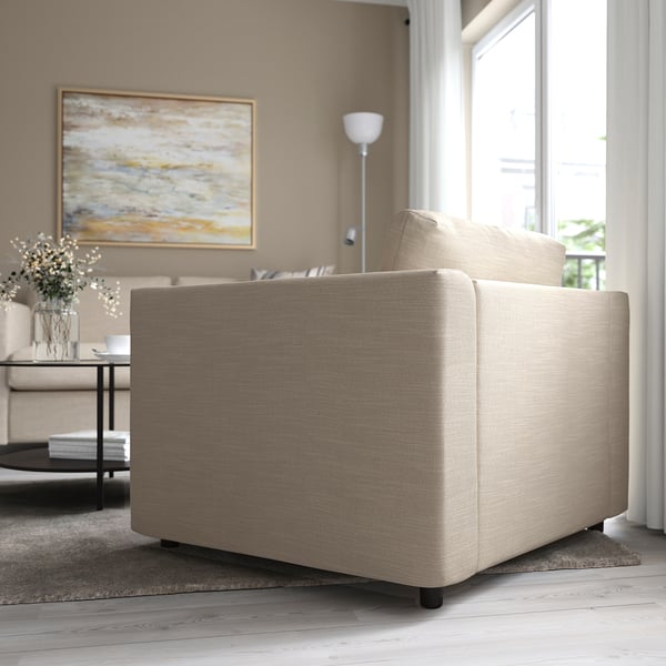 Beige sofa by large window with table, vase, and artwork.