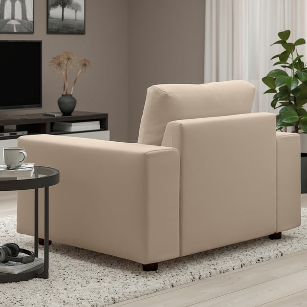 Modern living room with beige sofa, side table, coffee mug, headphones, vase, and plant.
