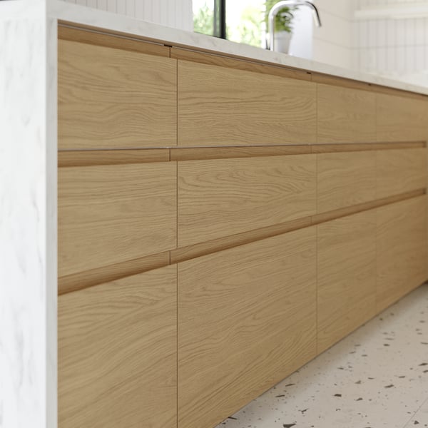 Wooden kitchen cabinets with sleek, light brown drawer fronts.