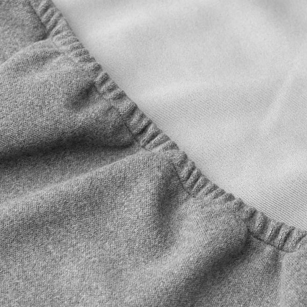 Close-up of grey polyester chair cover, smooth texture, tight stitches, over lightweight fabric chair.