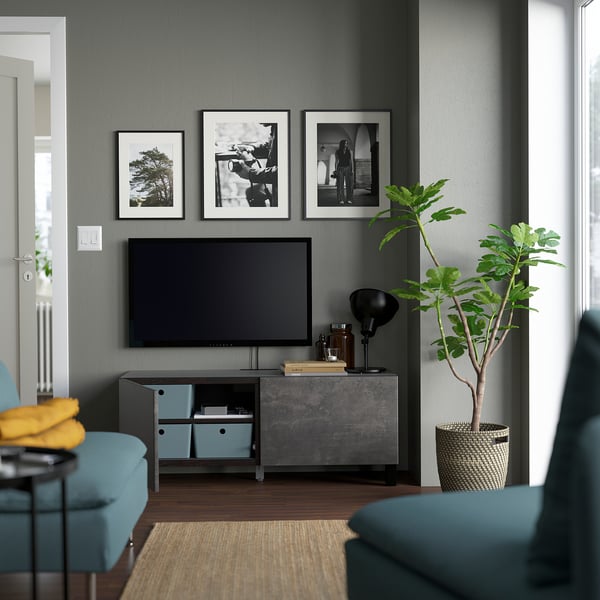 Modern living room with BESTÅ tv bench, adjustable shelves, cable management, and soft-closing drawers. Tv flanked by blue accents and a plant.