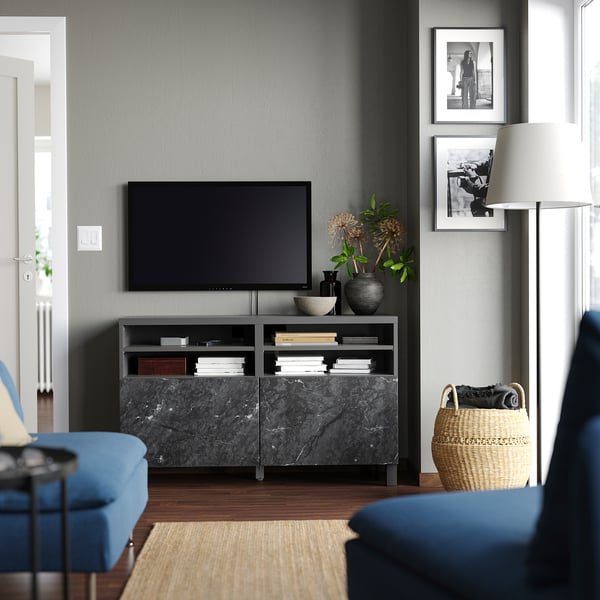 Modern living room BESTÅ tv stand in black and marble, with a flat screen tv, blue sofa, and decorations.
