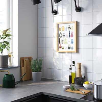 Modern kitchen with large poster of colourful vases behind counter, plants, and kitchen tools.
