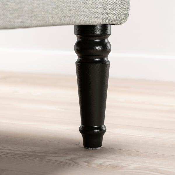 Black wooden chair leg with turned design on light wooden floor.