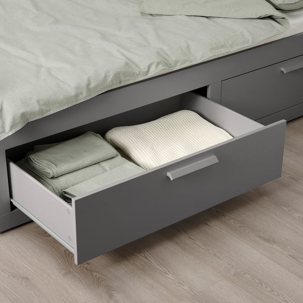 Under-bed drawer open, showing folded bed linens. Part of a space-saving bed system.