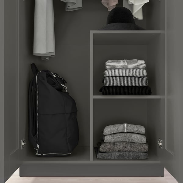 A grey wardrobe with a clothes rail and shelves storing folded clothes and a backpack.