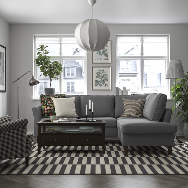 Grey EKHOLMA sectional sofa with clean lines, cushions, natural light, plants, and colourful pillows.