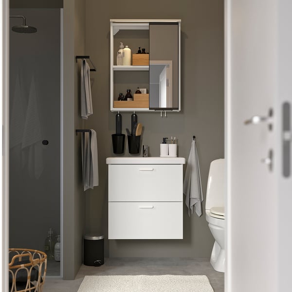 Modern bathroom with ENHET wall cabinet, sliding mirror, white washbasin, black accessories, and grey towels.