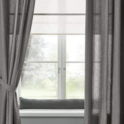 Modern window with grey curtains and cushion; minimalist design.