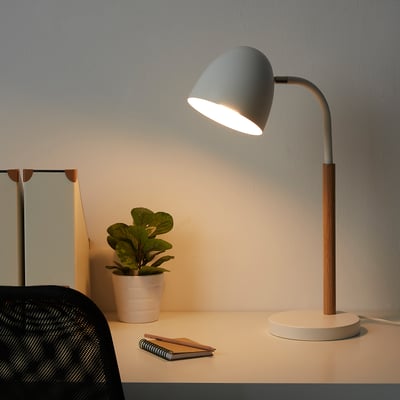 Modern desk lamp, FRANSALG, with greenish shade, wooden base. Light directs downwards. Plant and notes nearby.