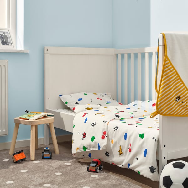 Bright blue room with white childs bed and colourful duvet, next to a stool and narrow shelf, efficiently maximising space.