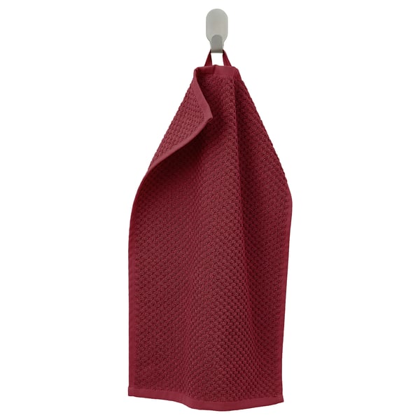 A burgundy GULVIAL towel hangs on a hook, textured, soft, and 100% cotton.