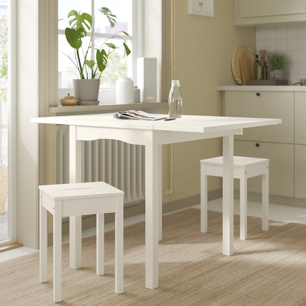 Small white kitchen set with foldable table and stools, perfect for limited spaces.