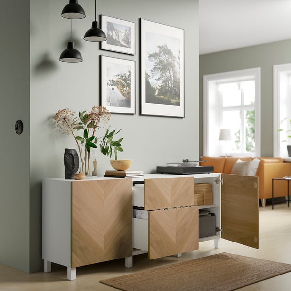Modern living room with wooden cabinet, record player, pendant lights, and nature photos.